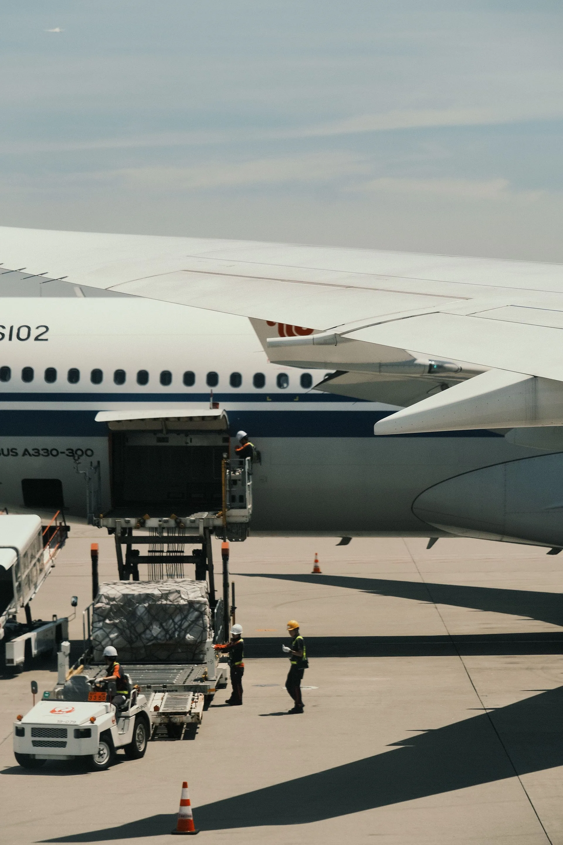 Airport ground crew loading cargo onto a wide-body freight aircraft